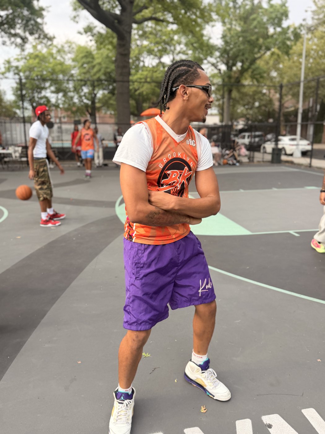 Player in an orange BK Net-Work jersey and sunglasses on the court
